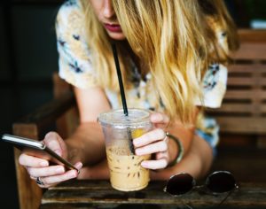woman with iced coffee and phone texting