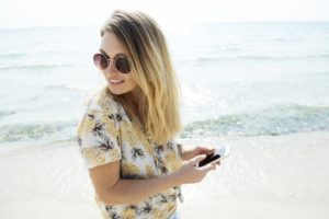 nő SMS a telefonon a tengerparton