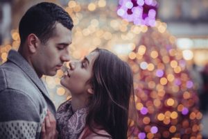 couple embracing near Christmas lights