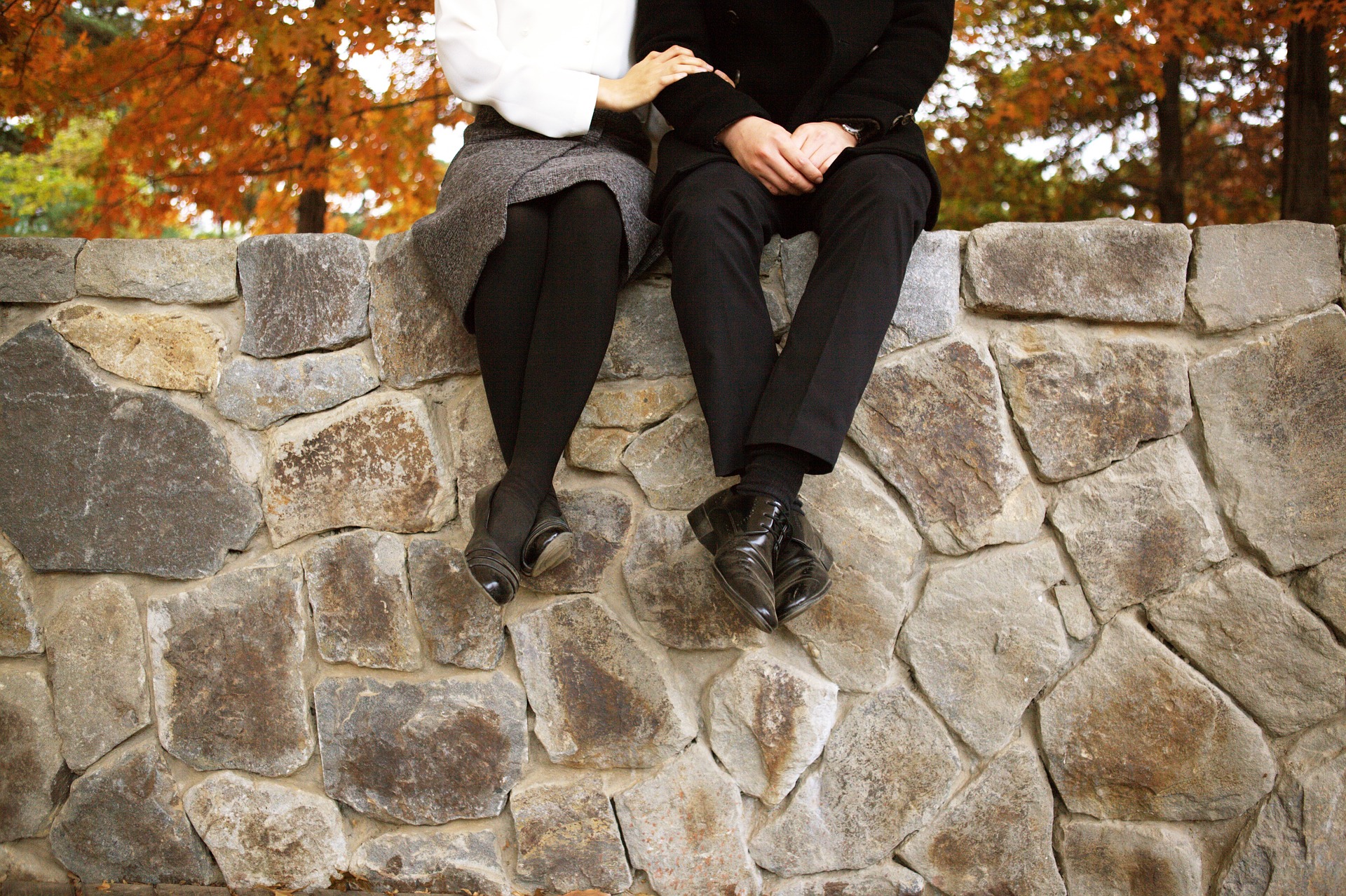 couple sitting on a stone wall in the autumn