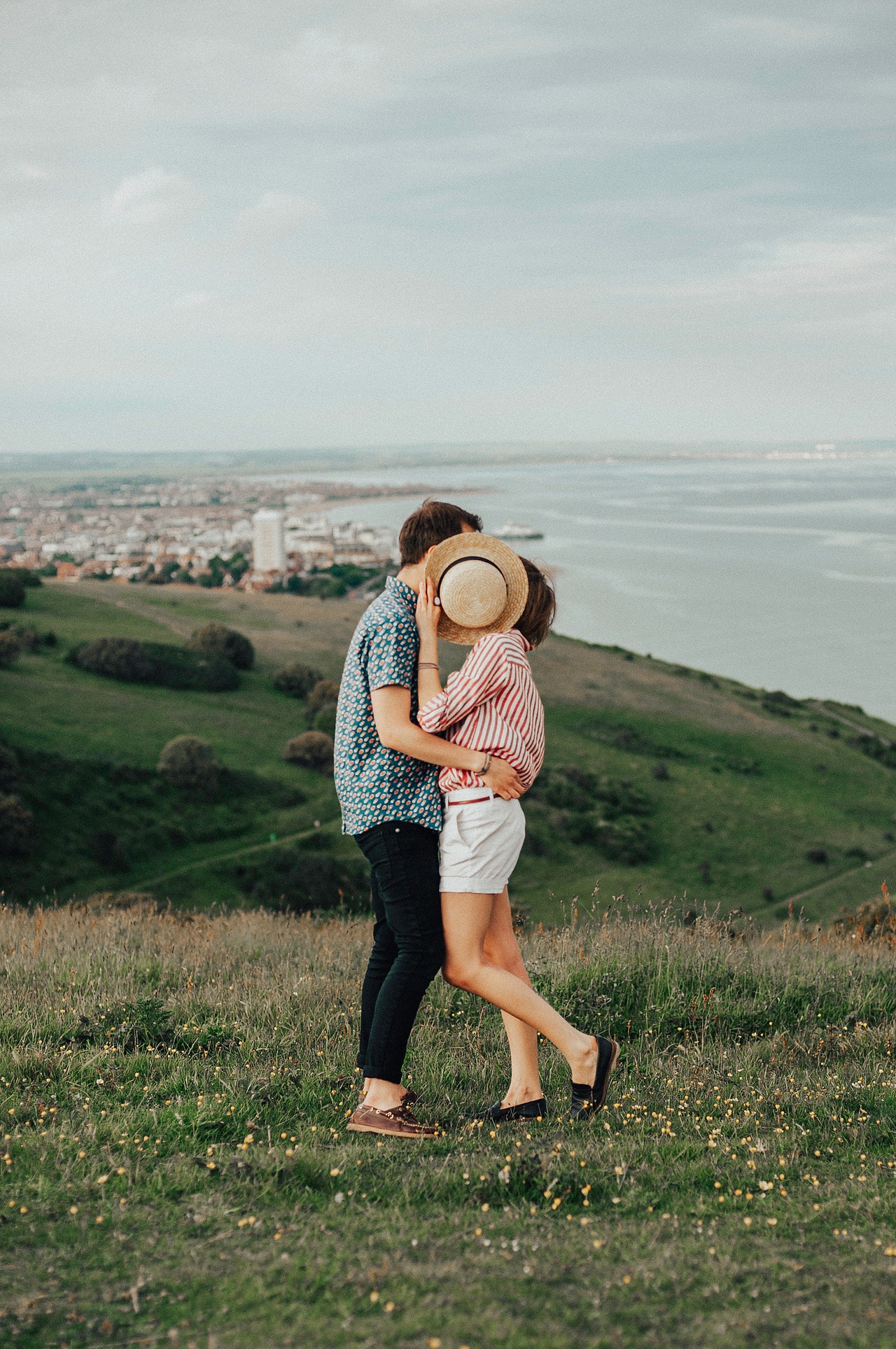 couple kissing behind a hat
